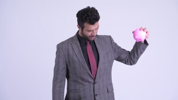 Stressado barbudo persa empresário segurando porquinho banco e dando polegares para baixo — Vídeo de Stock