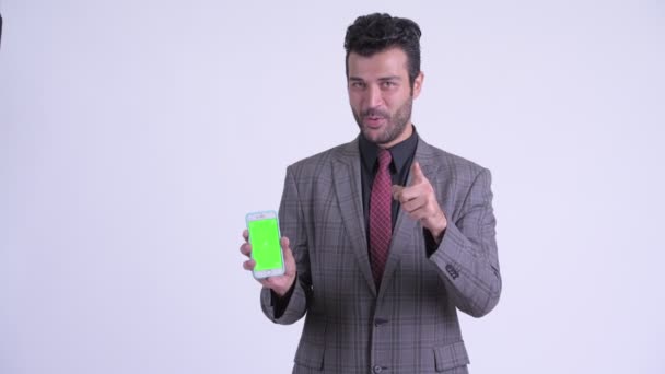 Счастливый бородатый персидский бизнесмен показывает телефон и показывает большие пальцы вверх — стоковое видео