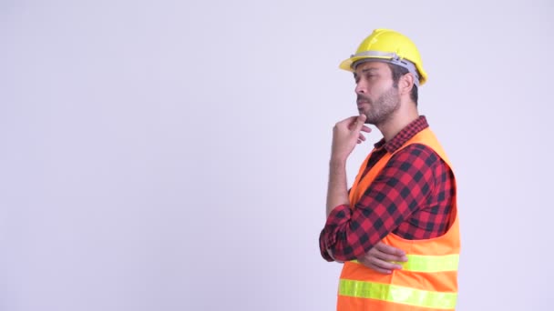 Vista de perfil de hombre persa barbudo feliz trabajador de la construcción pensando — Vídeos de Stock