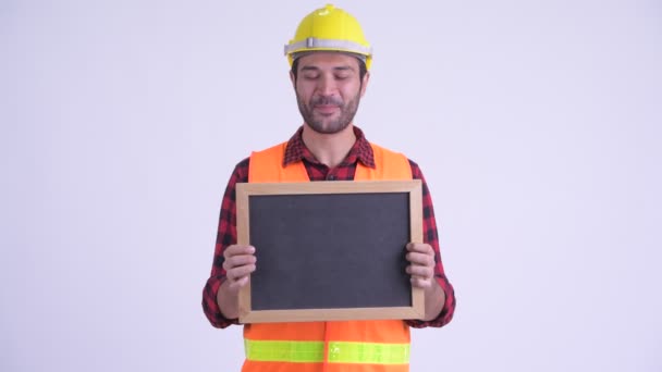 Happy bearded Persian man construction worker talking while holding blackboard — Stock Video