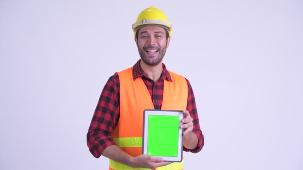 Feliz barbudo hombre persa trabajador de la construcción hablando mientras muestra tableta digital — Vídeo de stock