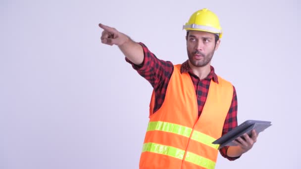 Guapo barbudo hombre persa trabajador de la construcción dirigiendo mientras se utiliza la tableta digital — Vídeos de Stock