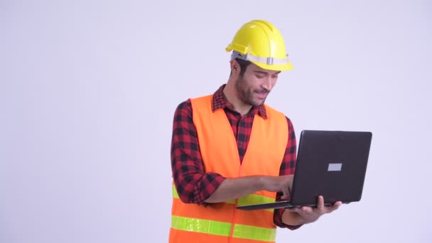 Gelukkig bebaarde Perzische man bouwvakker met behulp van laptop en het geven van duimen omhoog — Stockvideo