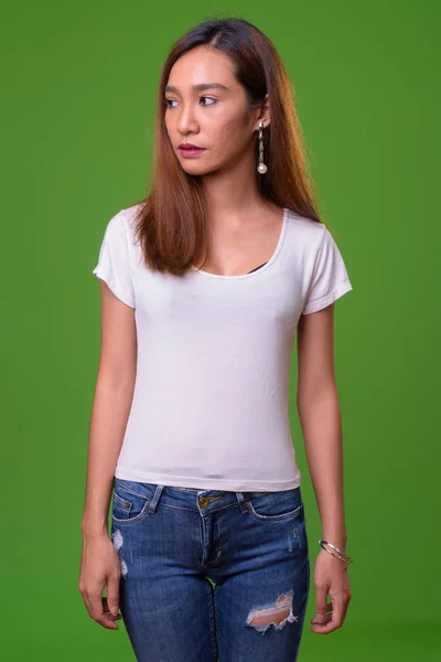 Young slim Asian woman against green background — Stok fotoğraf