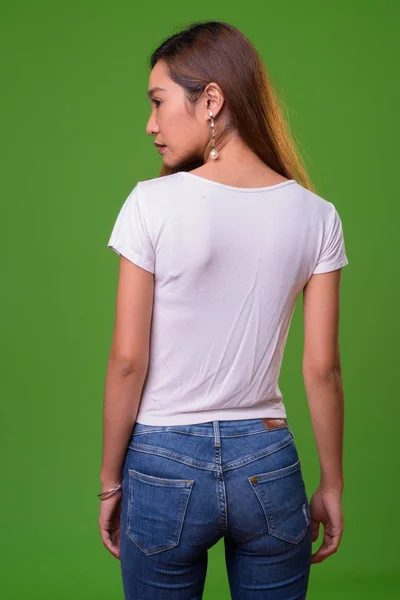 Young slim Asian woman against green background — Stockfoto