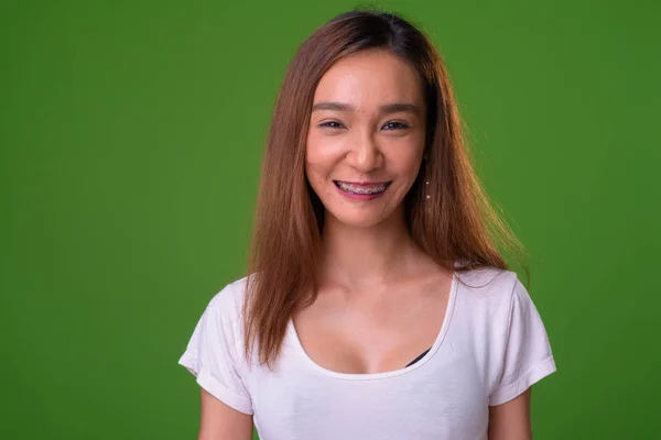 Young slim Asian woman against green background — 스톡 사진
