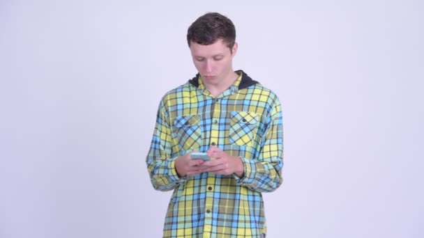 Mladý pohledný muž myšlení při používání telefonu — Stock video