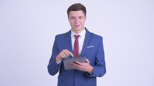 Szczęśliwy młody biznesmen za pomocą cyfrowego tabletu i dając kciuki w górę — Wideo stockowe