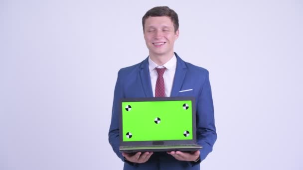 Feliz joven hombre de negocios guapo pensando mientras muestra el ordenador portátil — Vídeo de stock