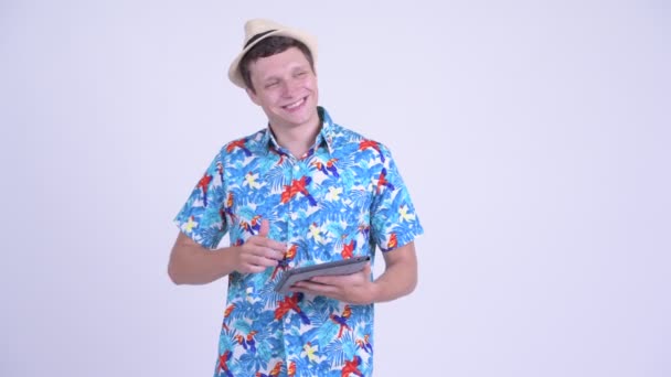 Feliz jovem bonito turista homem pensando ao usar tablet digital — Vídeo de Stock