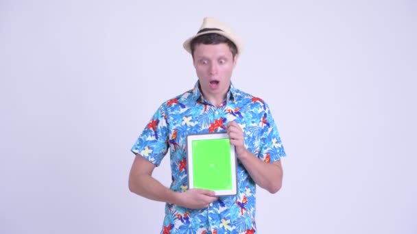Gelukkig jonge knappe toerist man toont digitale Tablet en op zoek geschokt — Stockvideo