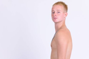 Studio shot of young handsome blonde man with tattoos shirtless against white background