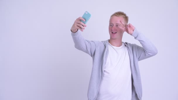 Boldog fiatal szőke férfi beszél selfie telefonnal — Stock videók