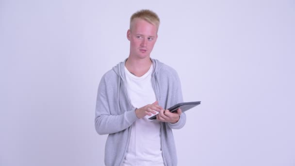 Ευτυχισμένος νέος ξανθός/ιά όμορφος άνθρωπος σκέψης ενώ χρησιμοποιεί ψηφιακό δισκίο — Αρχείο Βίντεο