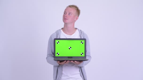 Happy young blonde handsome man thinking while showing laptop — Stock Video