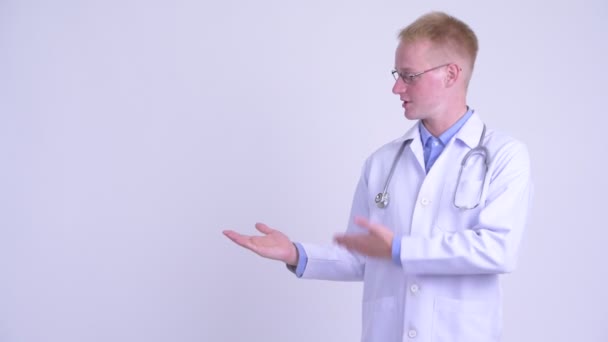 Happy young blonde man doctor showing something — Stock Video