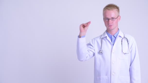 Boldog fiatal szőke férfi orvos harapós ujjak és mutat valamit — Stock videók