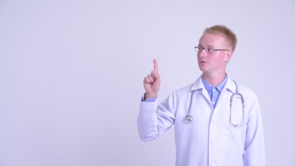 Счастливый молодой блондин врач думает, указывая вверх — стоковое видео