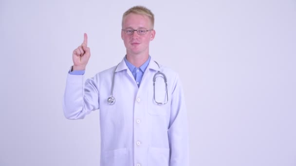 Feliz joven rubia hombre médico señalando hacia arriba — Vídeos de Stock