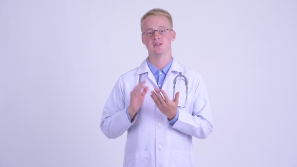 Gelukkige jonge blonde man arts die iets uitlegt — Stockvideo