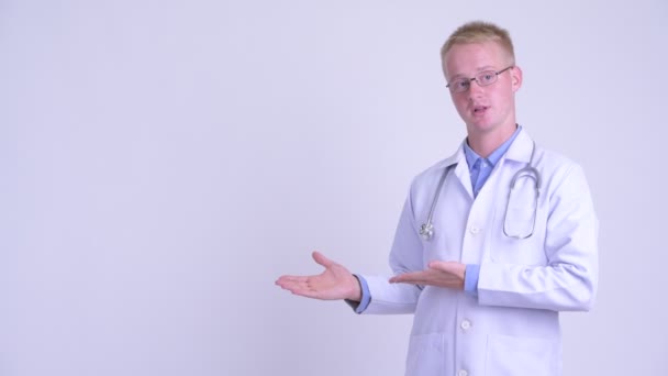 Junger blonder Mann Arzt präsentiert etwas — Stockvideo