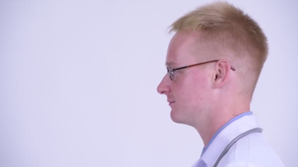 Profile view of happy young blonde man doctor thinking — Stock Video