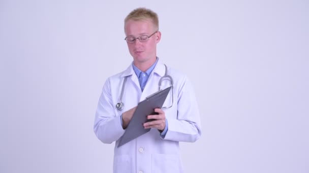 Jong blond man arts praten terwijl het lezen op klembord — Stockvideo