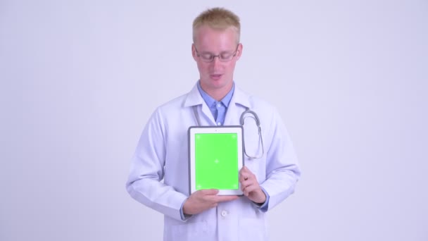 Triste jovem loira médico falando enquanto mostra tablet digital — Vídeo de Stock