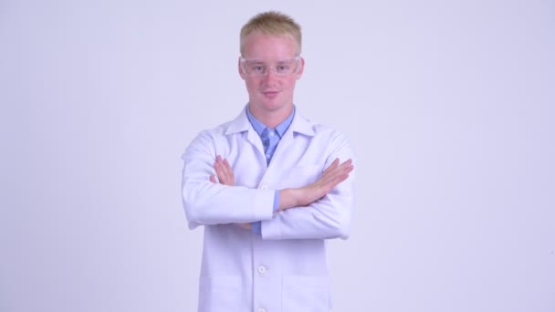 Happy young blonde man doctor wearing protective glasses with arms crossed — Stock Video