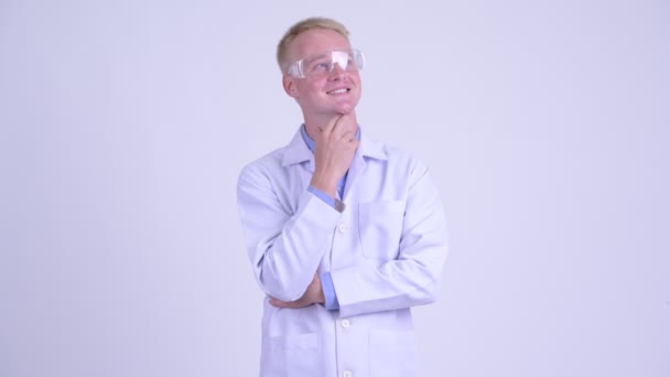 Heureux jeune homme blond médecin avec des lunettes de protection penser — Video