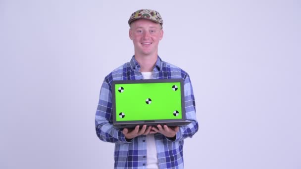 Šťastný mladý pohledný hipíček, který mluví, když zobrazuje laptop — Stock video