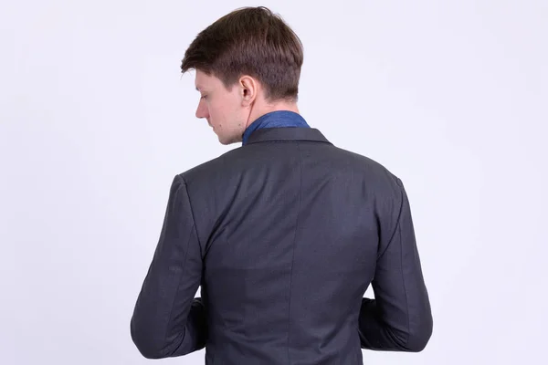 Rückansicht eines jungen hübschen Geschäftsmannes im Anzug, der über die Schulter schaut — Stockfoto