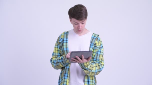 Glücklicher junger gutaussehender Mann denkt während er digitales Tablet benutzt — Stockvideo