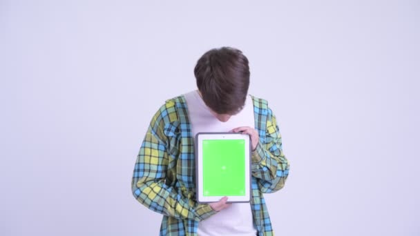 Glücklicher junger gutaussehender Mann zeigt digitales Tablet und wirkt überrascht — Stockvideo