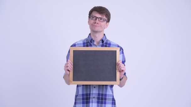 Feliz jovem hipster homem pensando enquanto segurando quadro negro — Vídeo de Stock
