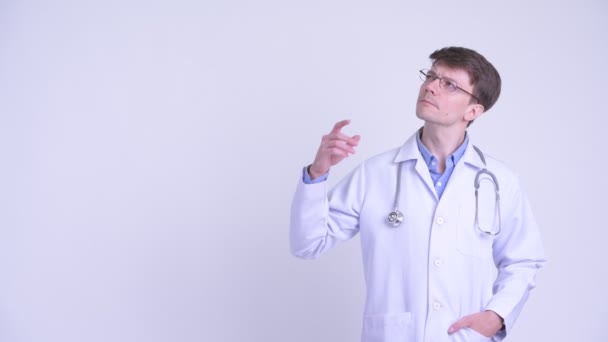 Счастливый молодой человек врач думает и указывает вверх — стоковое видео