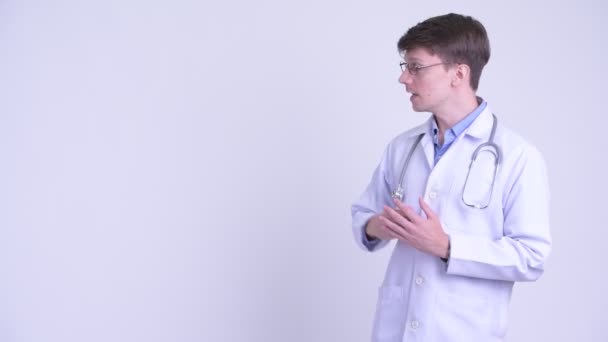 Jovem feliz bonito homem médico apresentando algo — Vídeo de Stock