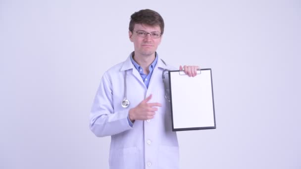 Serious young man doctor showing clipboard and giving thumbs down — Stock Video