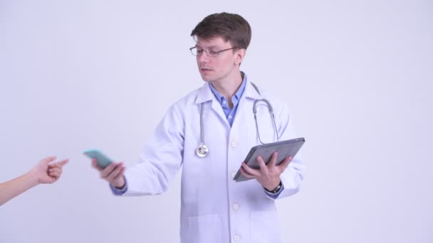 Ευτυχισμένος νεαρός γιατρός μιλάει στο τηλέφωνο και χρησιμοποιώντας το ψηφιακό δισκίο — Αρχείο Βίντεο