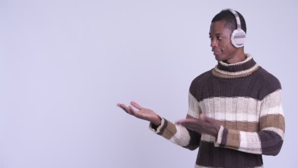Ung glad afrikansk man visar något redo för vintern — Stockvideo