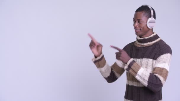 Fiatal boldog afrikai férfi ujjal mutogatva és mutatva valamit készen áll a télre — Stock videók