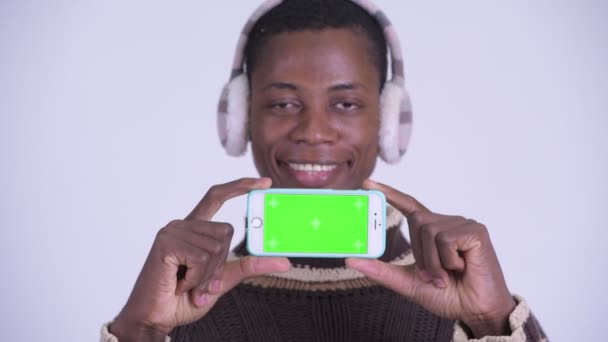 面对年轻的快乐非洲男子显示手机准备冬天 — 图库视频影像