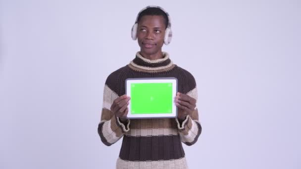 Młody szczęśliwy Afryki człowiek myślenie pokazując cyfrowy tablet gotowy na zimę — Wideo stockowe
