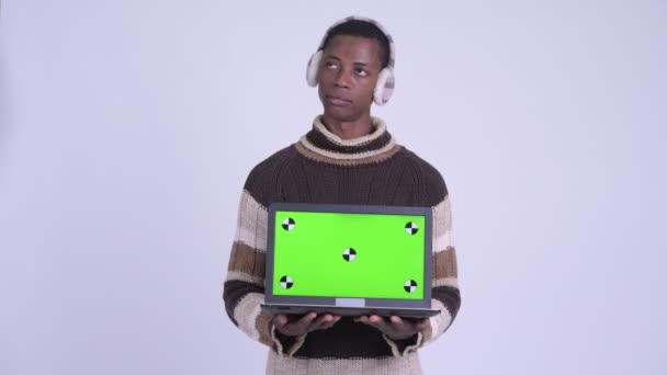 Genç mutlu Afrikalı adam laptopun kışa hazır olduğunu gösterirken düşünüyor — Stok video