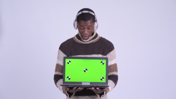 Jong gelukkig Afrikaans man tonen laptop en kijken verrast klaar voor de winter — Stockvideo