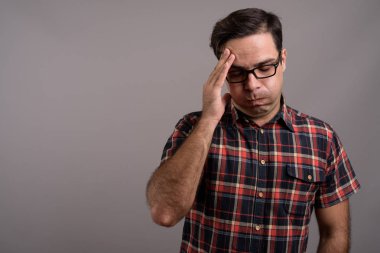 Studio shot of handsome Persian man wearing eyeglasses against gray background