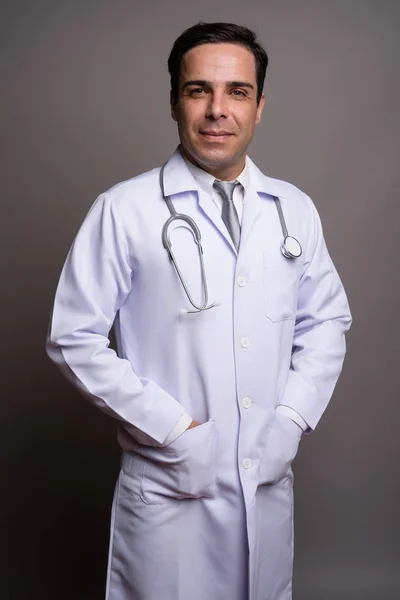 Handsome Persian man doctor against gray background — Stock Photo, Image