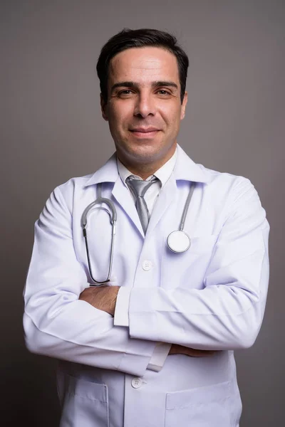 Handsome Persian man doctor against gray background — Stock Photo, Image