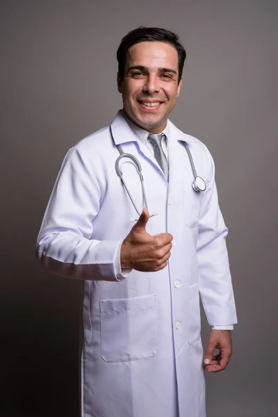 Schöner persischer Mann Arzt vor grauem Hintergrund — Stockfoto
