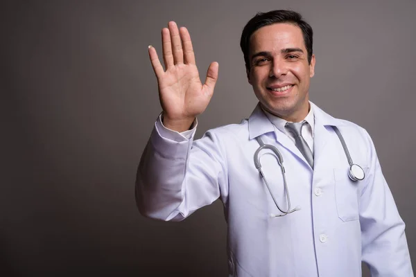 Knappe Perzische man arts tegen grijze achtergrond — Stockfoto